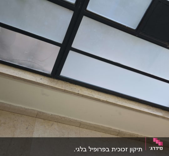 חלון זכוכית עם מסגרת מתכת ליד רצפת שיש